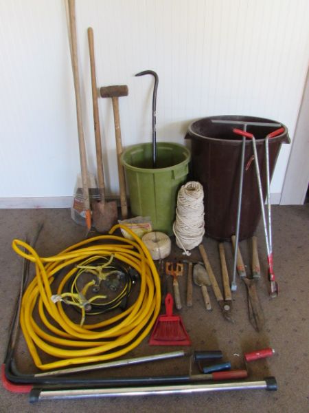 TRASH CAN FILLED WITH GARDEN TOOLS.