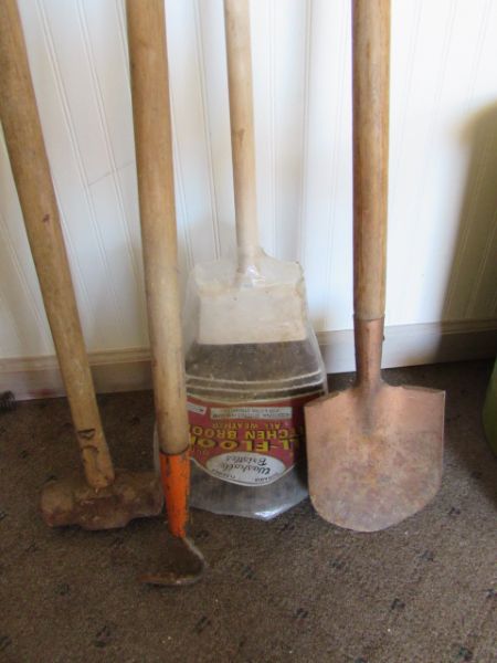 TRASH CAN FILLED WITH GARDEN TOOLS.