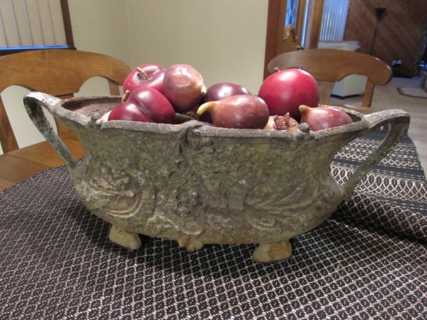 ANTIQUE VINTAGE RUSTY FOUR-LEGGED CAST IRON OVAL POT WITH HANDLES, FILLED WITH DECORATIVE FRUIT, CERAMIC PUMPKIN FIGURINES, AND TABLE RUNNER